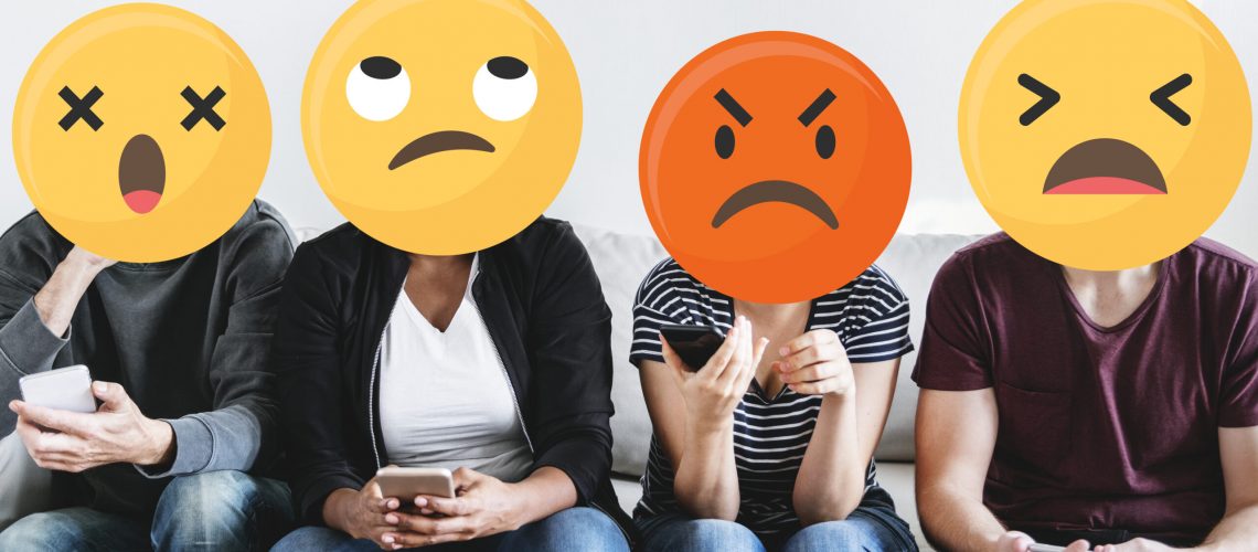 Diverse people with negative emoticons using mobile phones